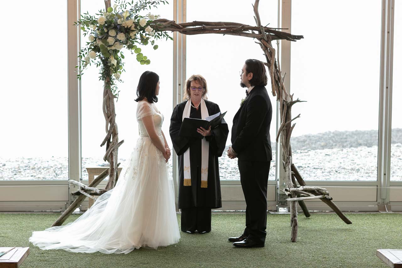 Megan and Andrew with the officiant during the wedding ceremony closeup