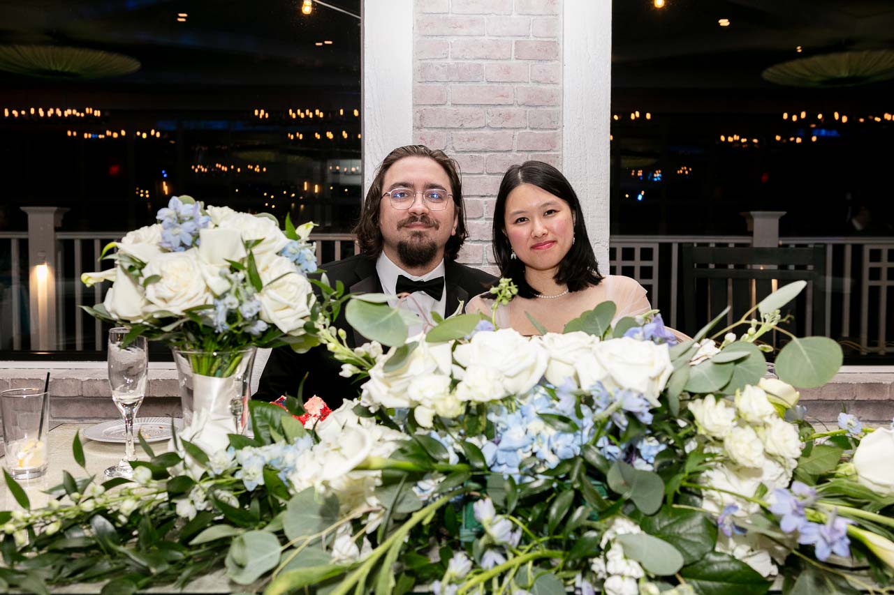 Megan and Andrew at the sweetheart table surrounded by flowers